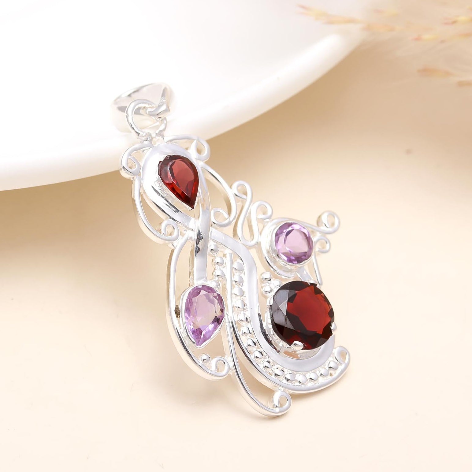 A 925 sterling silver pendant featuring an amethyst and garnet stone design, displayed against a soft background.