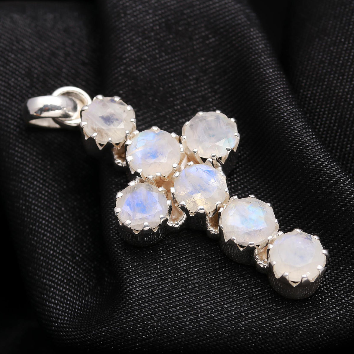 Silver pendant with rainbow moonstone stones on a black fabric background