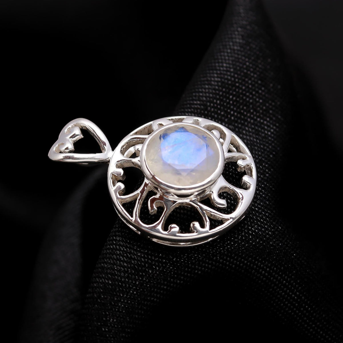Silver pendant with a moonstone on a black fabric background
