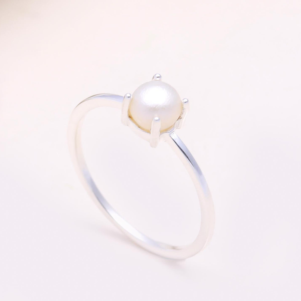 Pearl ring on a light pink background