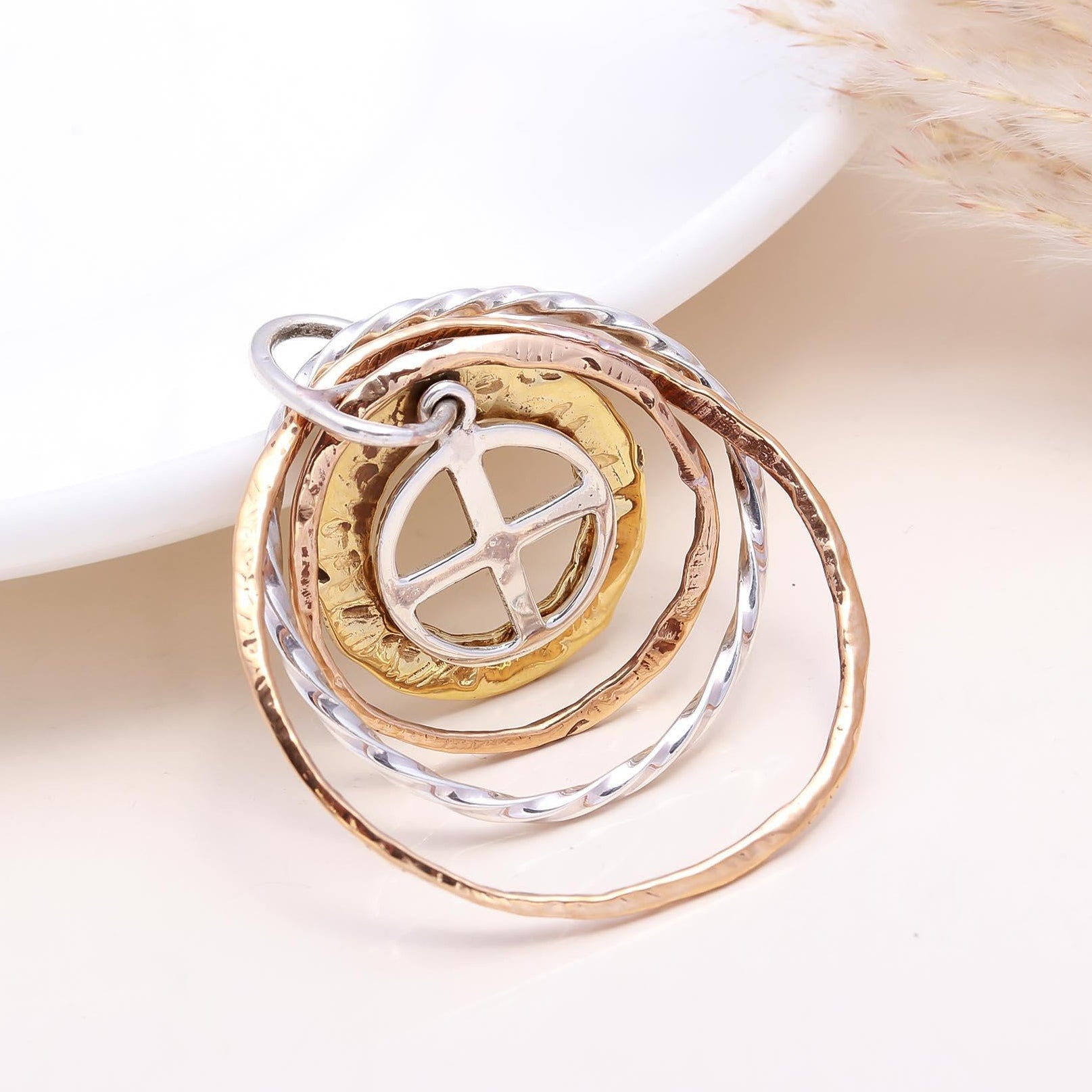 Three circular pendants in gold, silver, and rose gold on a white background