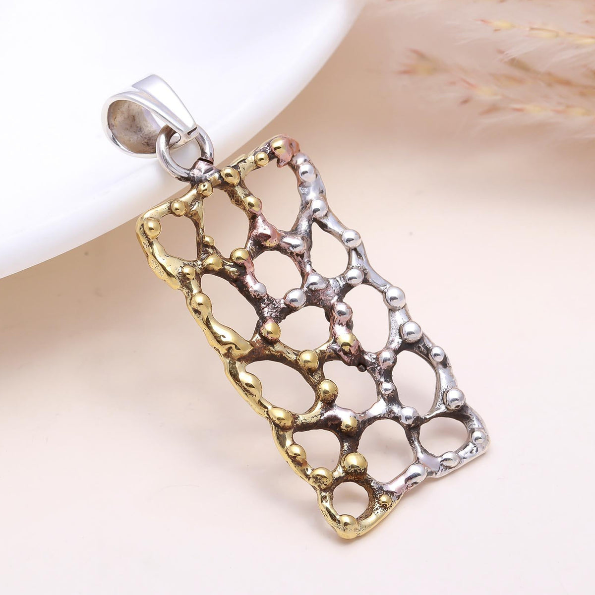 Two-tone silver and gold pendant on a white background