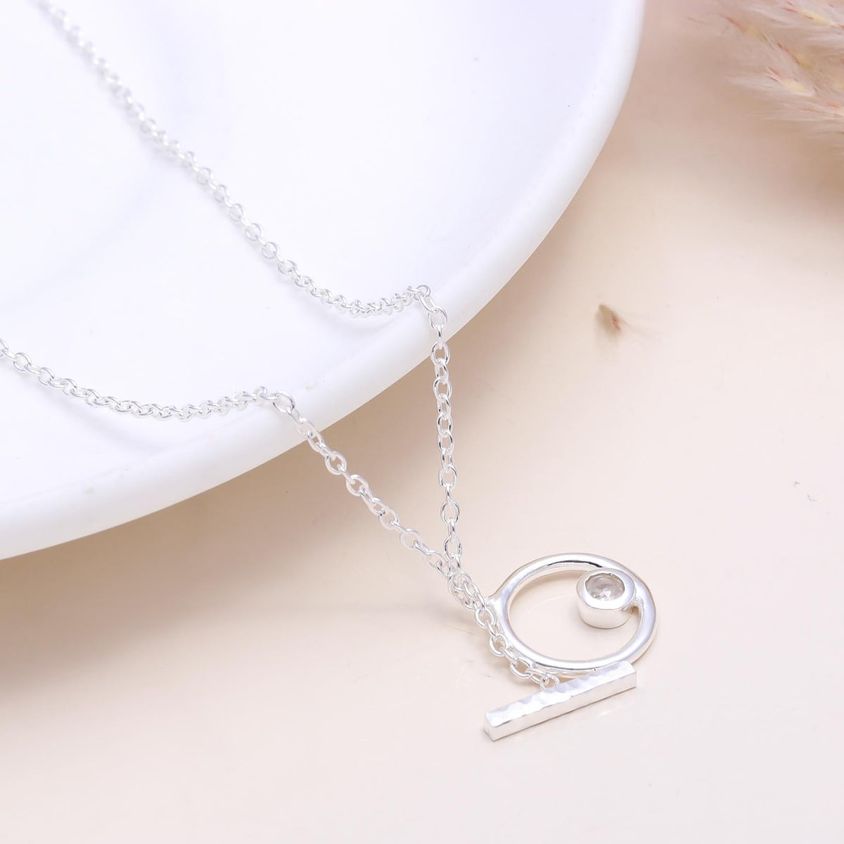 A 925 sterling silver circle pendant necklace laid out on a white surface, showcasing the minimalist design with a polished finish.