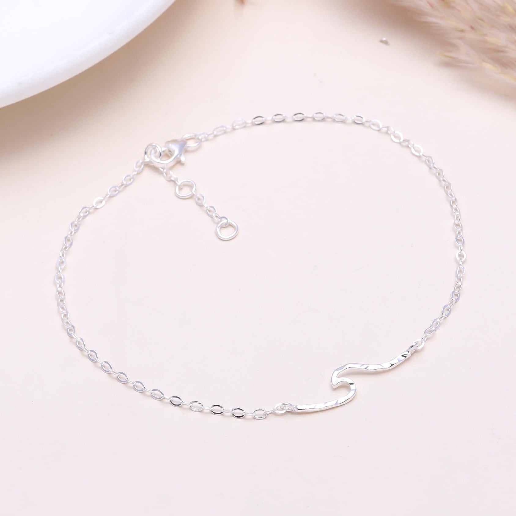 A 925 sterling silver wave chain bracelet displayed on a light background, with delicate wave-like links and an adjustable clasp.