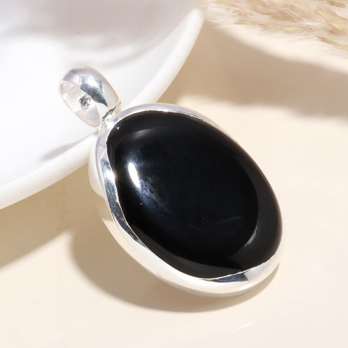 An oval black onyx gemstone pendant set in a 925 sterling silver mounting, displayed against a light background.