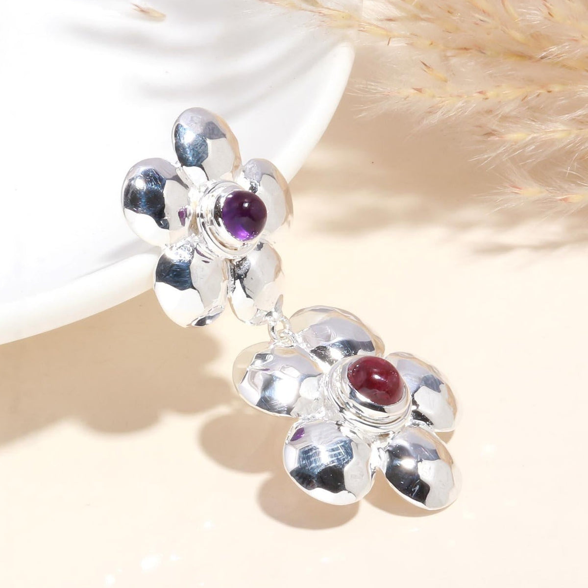 Silver floral pendant with gemstones on a neutral background