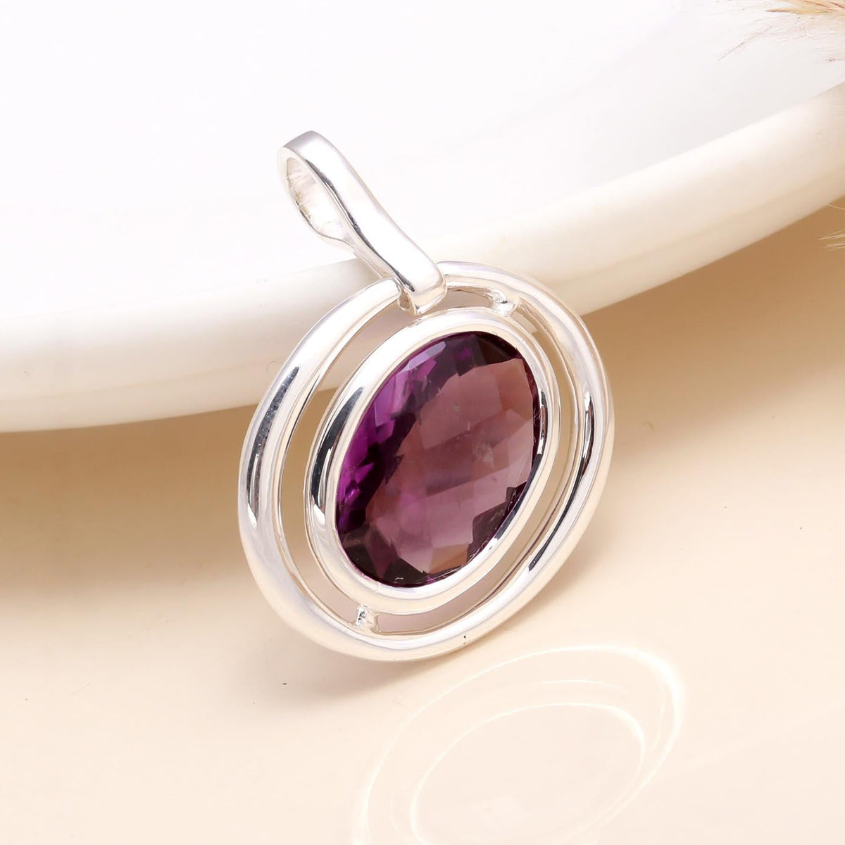A sterling silver double frame oval pendant with an amethyst gemstone, displayed against a light background.