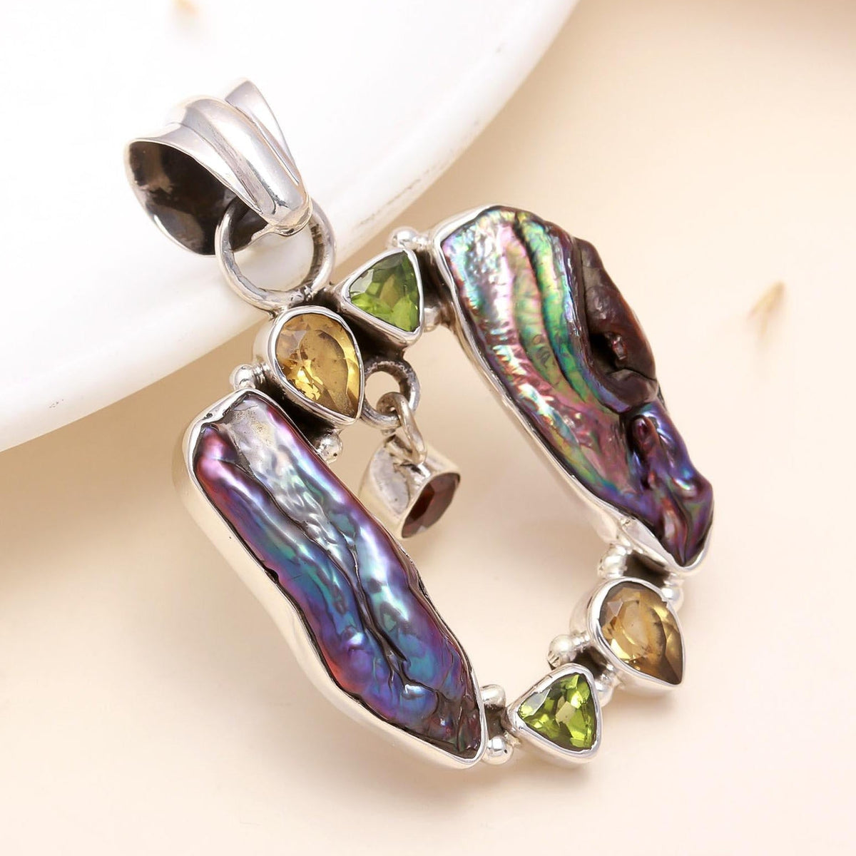 A baroque pearl pendant with multi-colored gemstone accents, crafted in sterling silver, displayed against a neutral background.