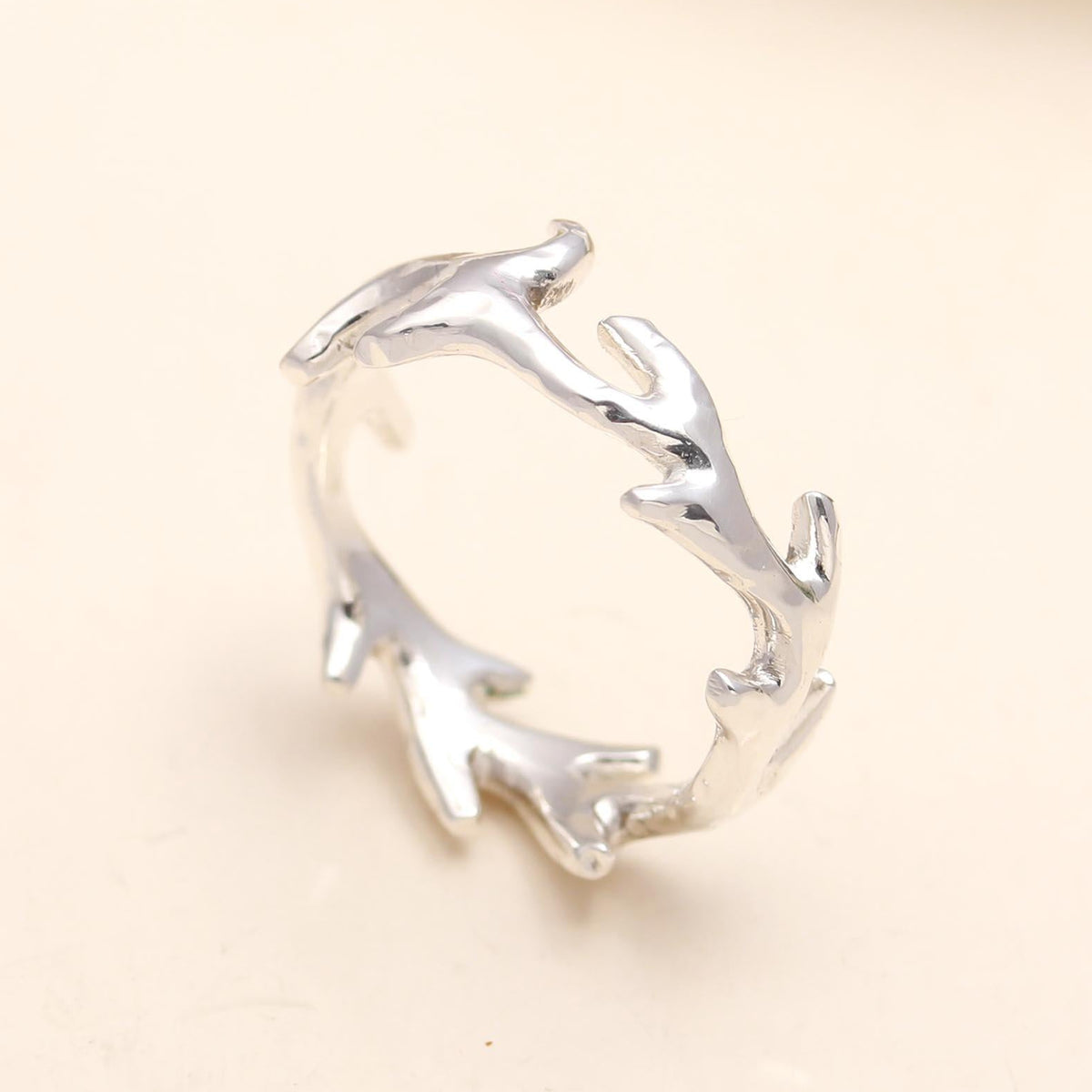 Silver branch-like ring on a beige background