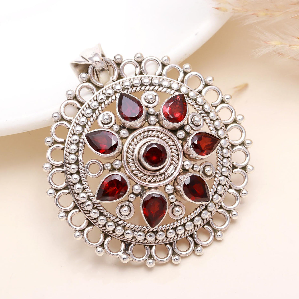 A vintage-style sterling silver pendant with multiple red garnet gemstones set within detailed filigree work.
