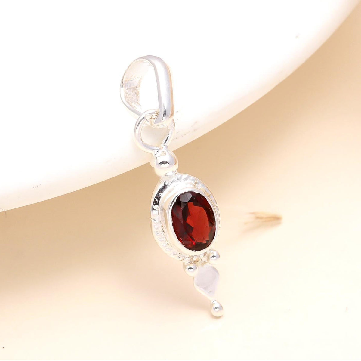 A 925 Sterling Silver pendant with a natural red garnet gemstone, set in a classic and minimalistic design.
