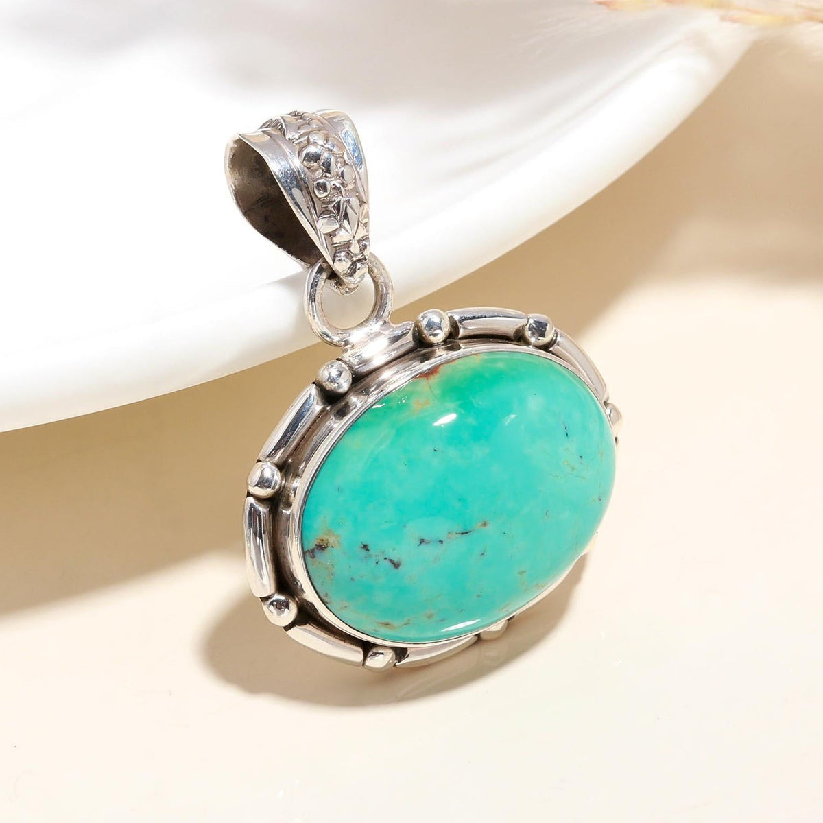 A vintage-style sterling silver pendant with an oval turquoise gemstone, displayed against a neutral background.