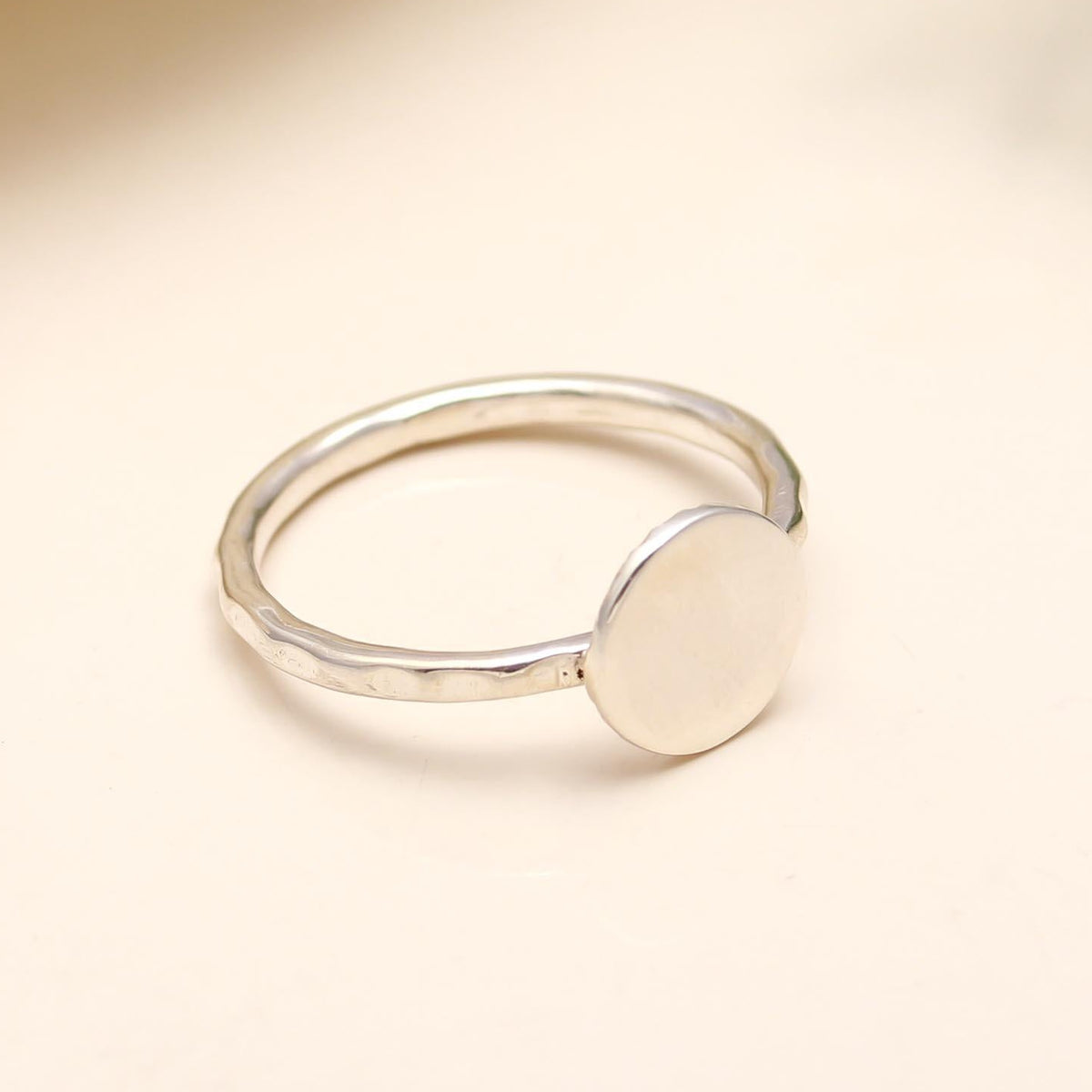 Silver ring with a circular design on a beige background