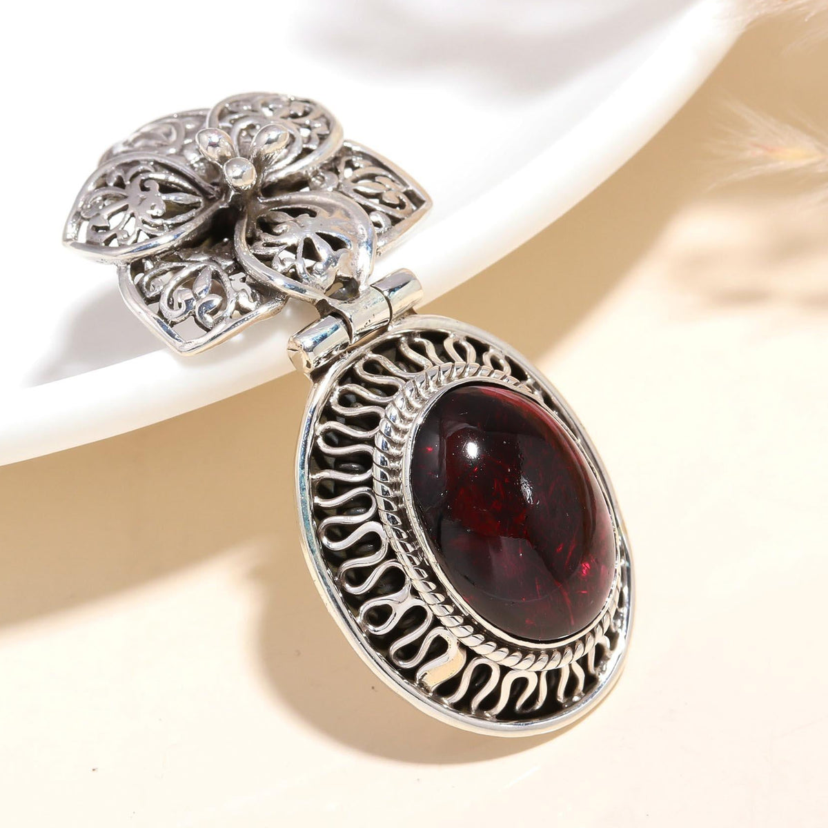 A vintage-inspired 925 sterling silver pendant with a deep red garnet gemstone and intricate filigree detailing.