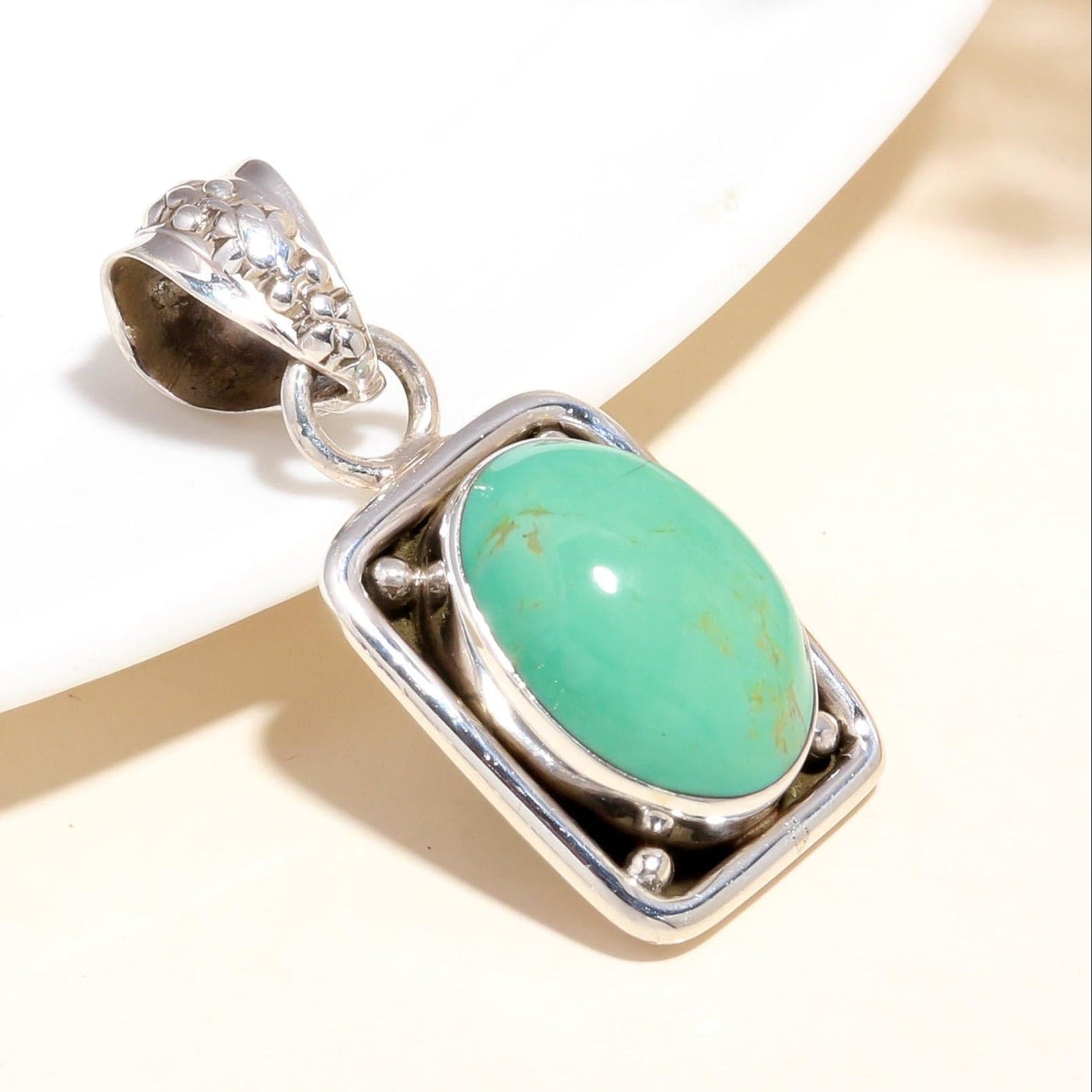 A 925 Sterling Silver Pendant with an oval green turquoise gemstone, featuring intricate handcrafted details.