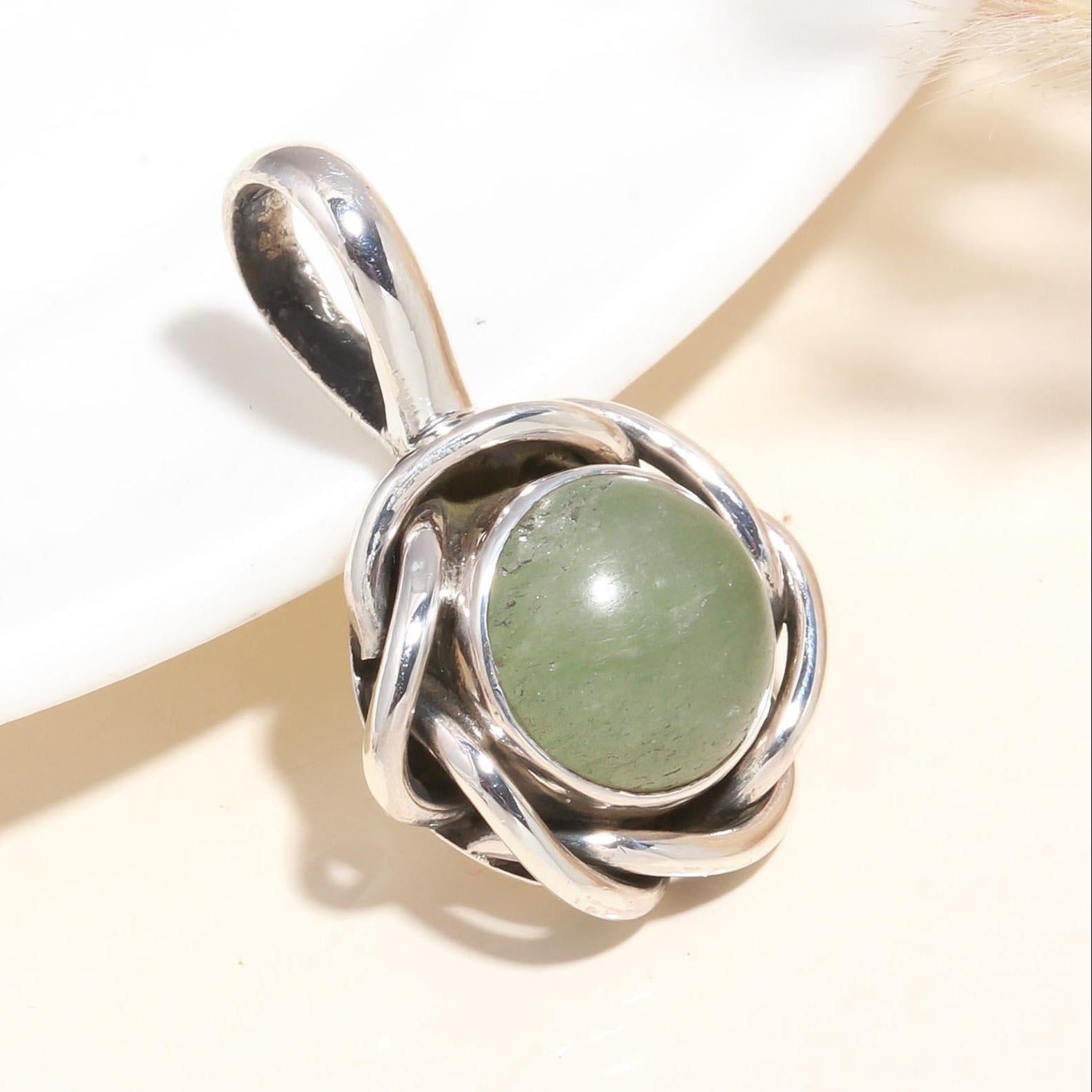 A 925 Sterling Silver pendant with a handmade Celtic knot design and a natural green Aventurine gemstone at its center, displayed against a neutral background.