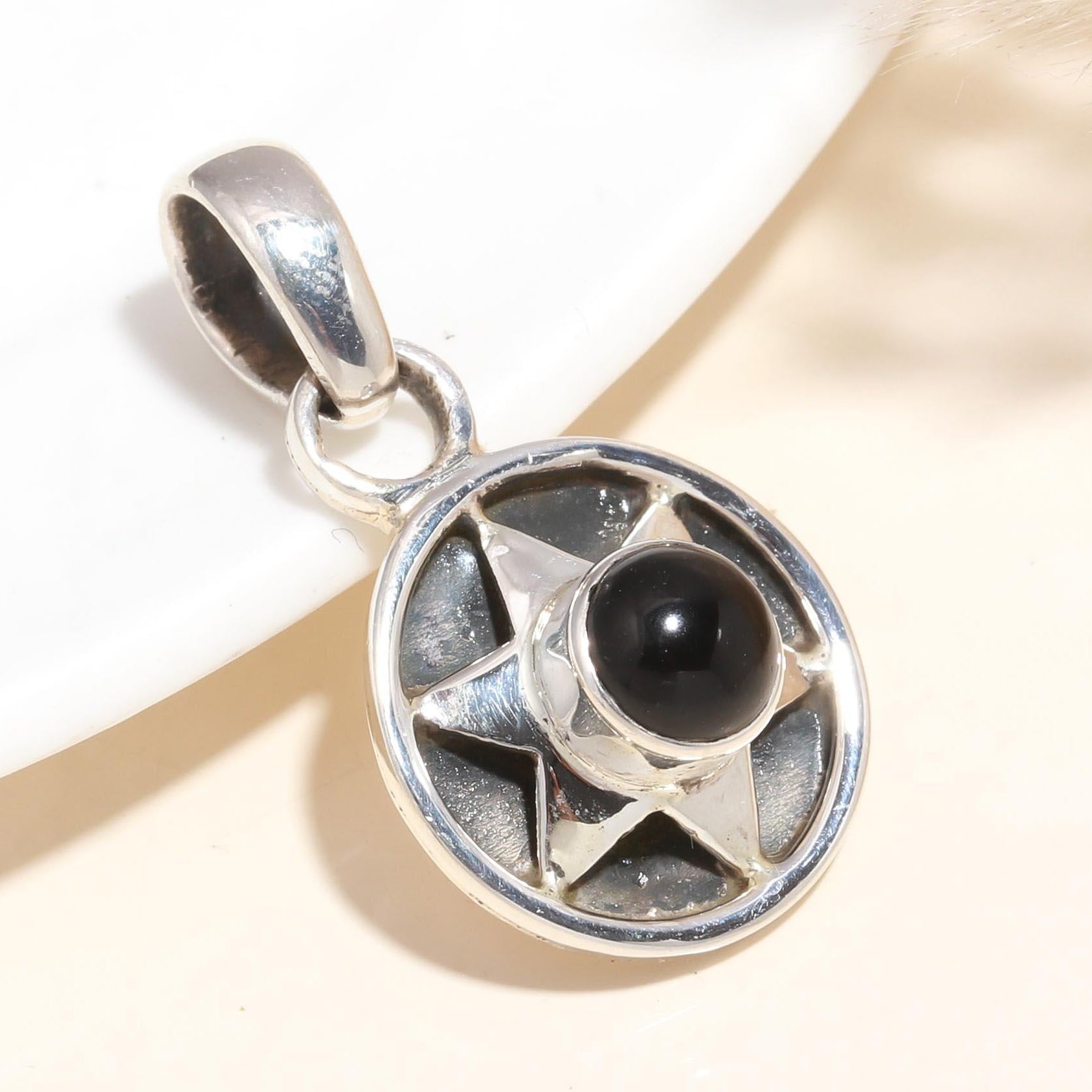 A 925 Sterling Silver Black Onyx gemstone set in a star-shaped pendant, displayed against a neutral background.