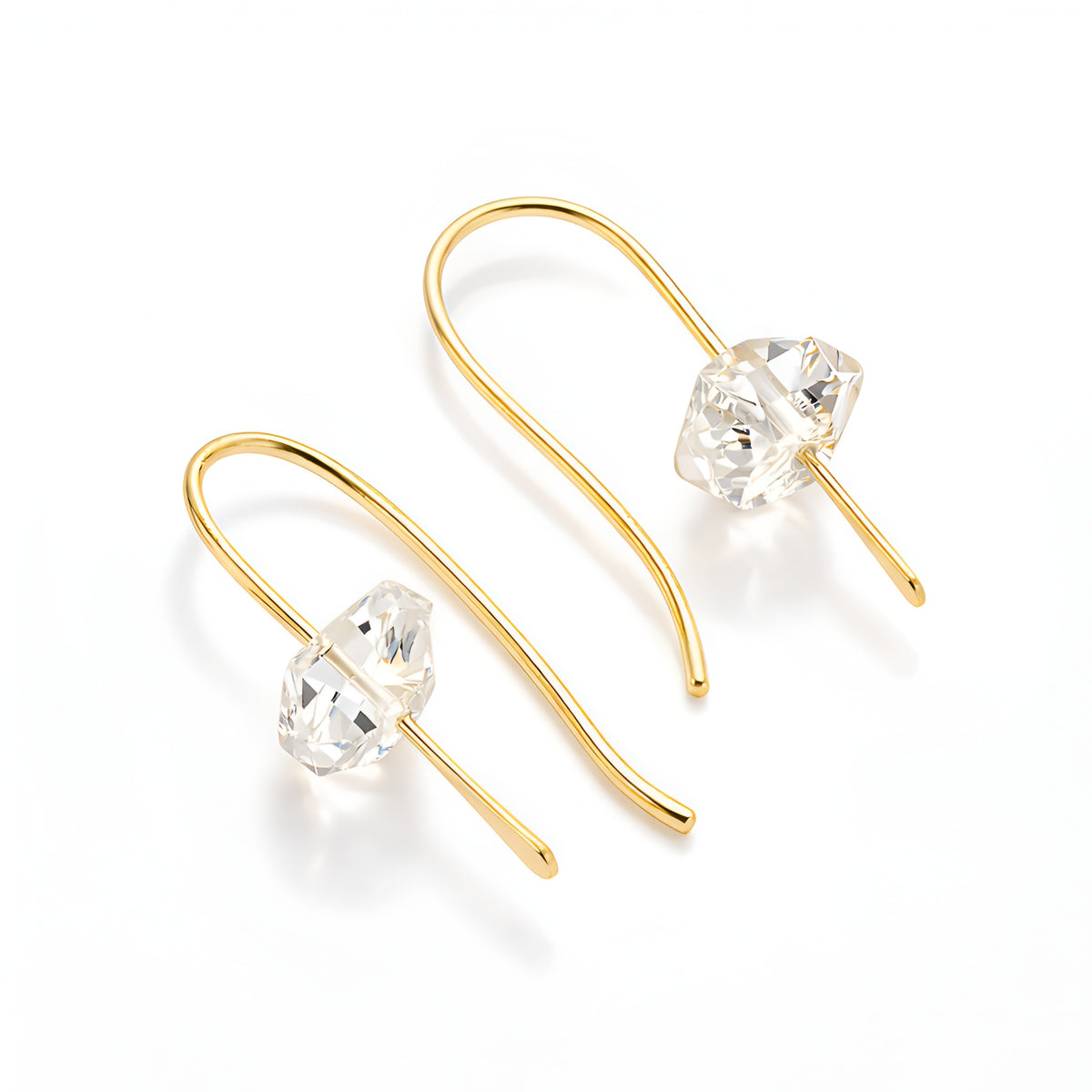 Gold earrings with clear gemstones on a white background