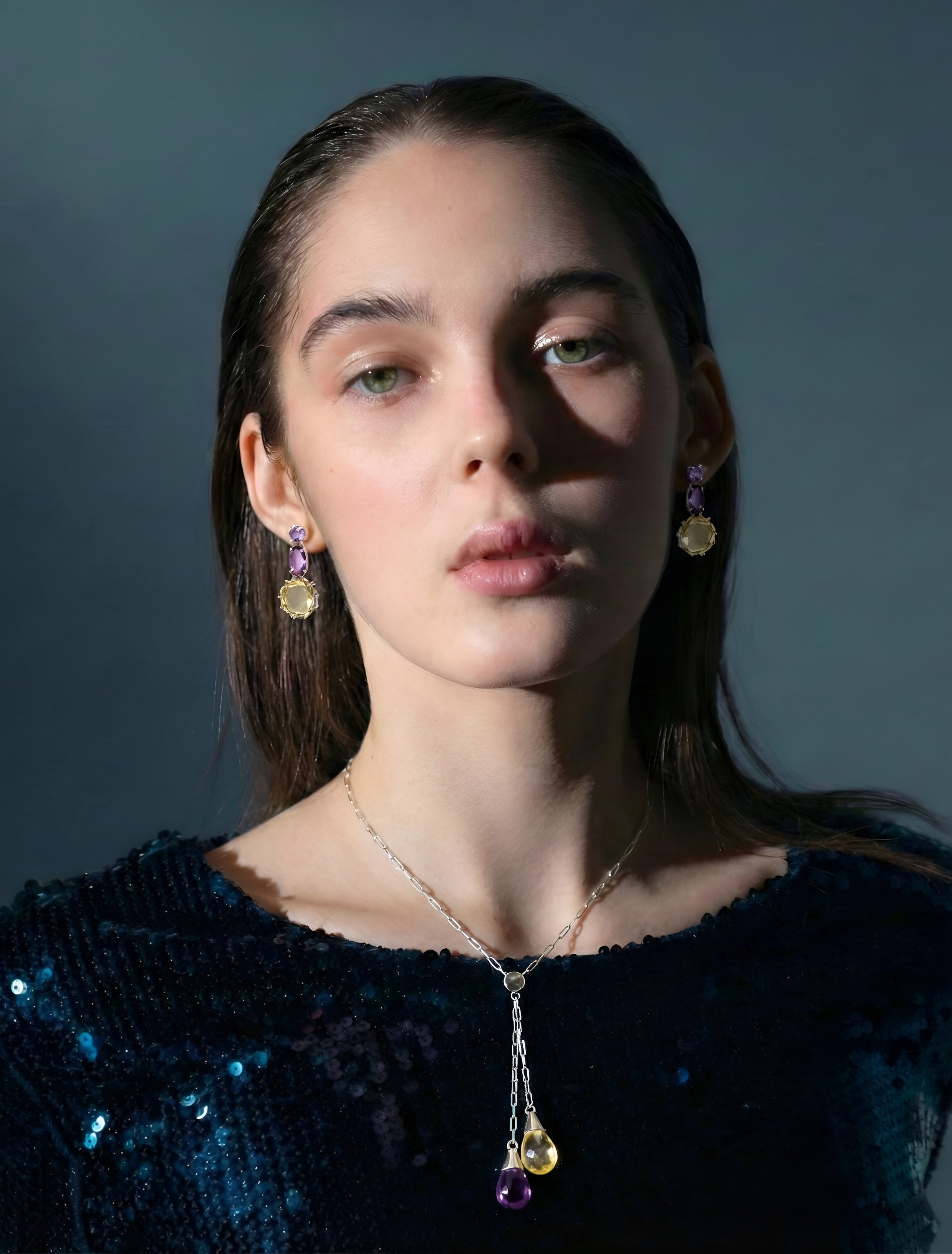 Woman wearing a necklace and earrings against a dark background