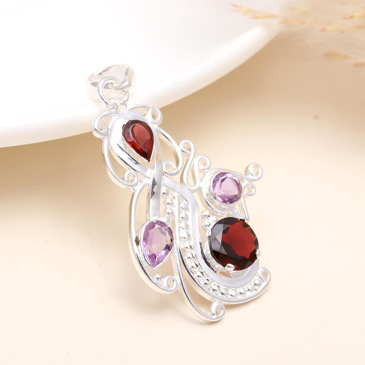A 925 sterling silver pendant featuring an amethyst and garnet stone design, displayed against a soft background.