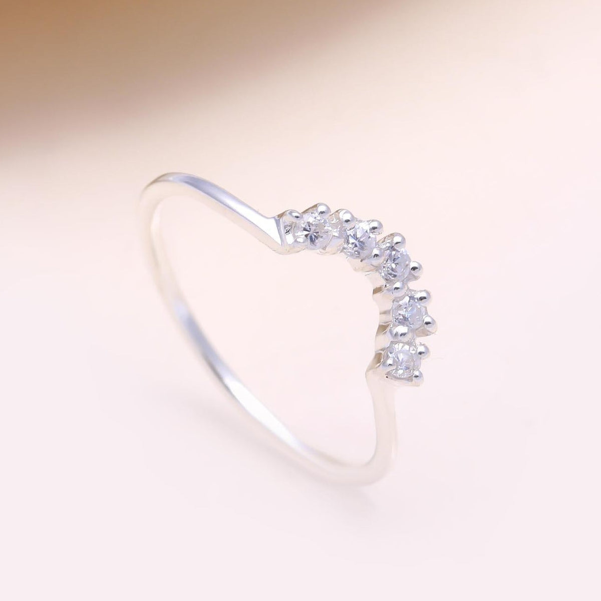Silver ring with small diamonds on a light pink background