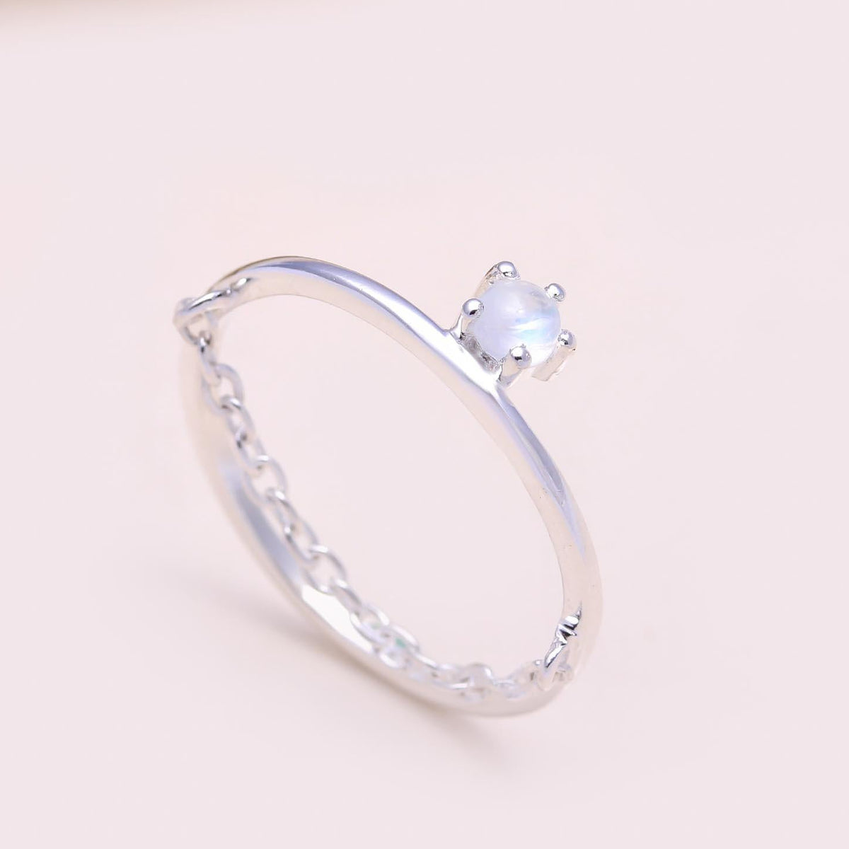 Silver ring with a gemstone on a light pink background