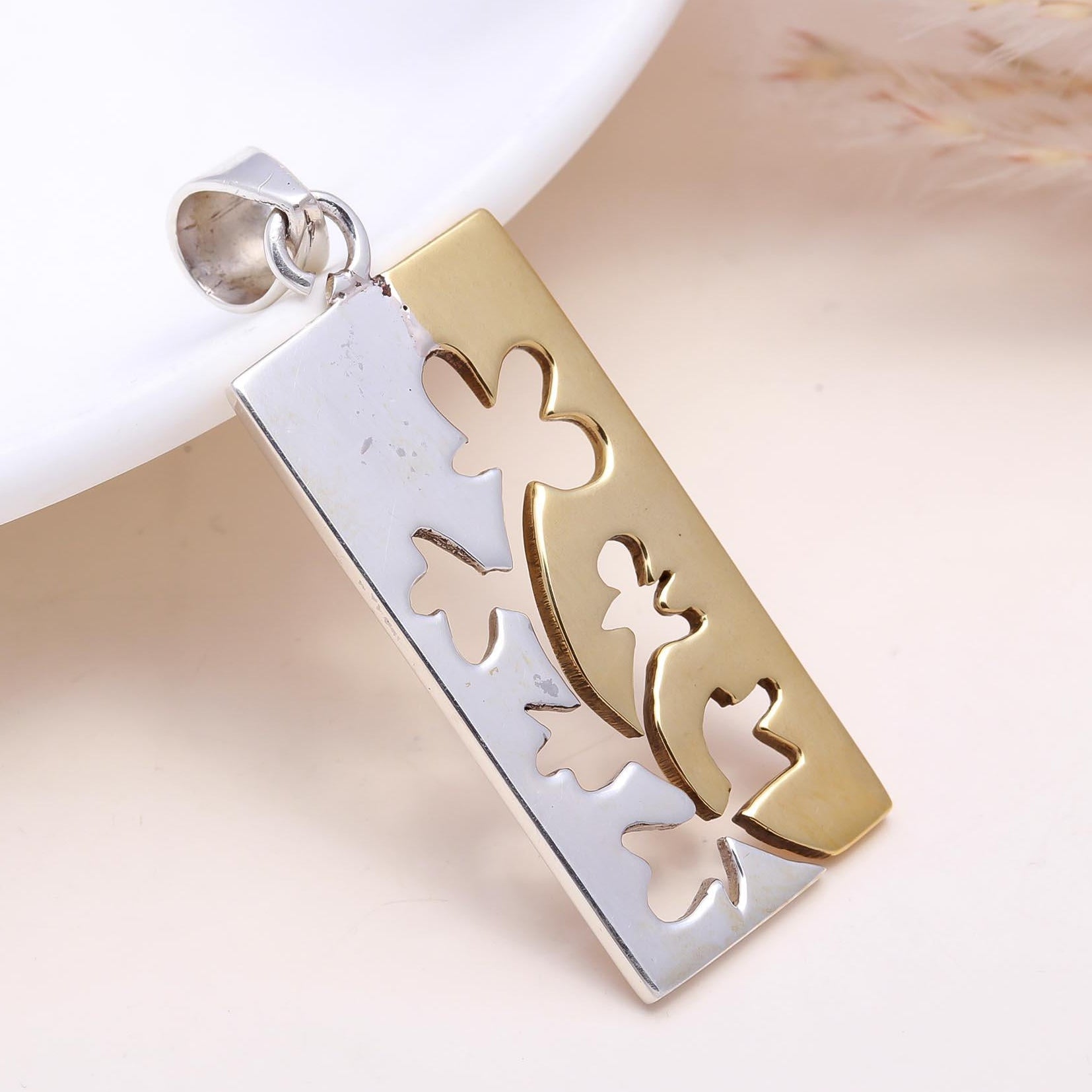 Gold and silver pendant with floral designs on a white background