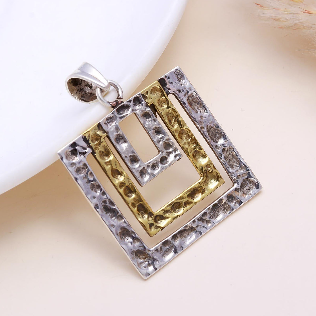 Gold and silver pendant on a light background