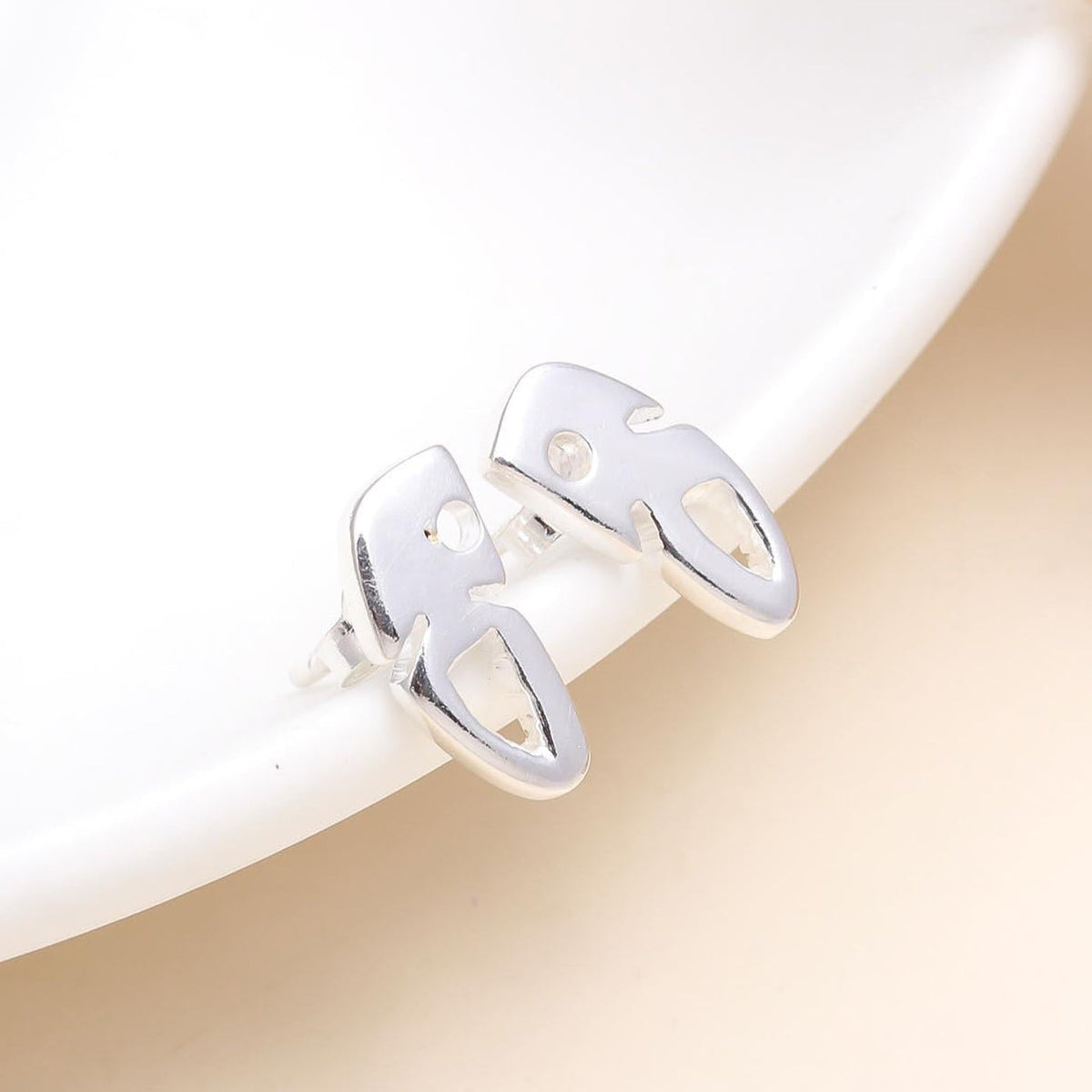 A pair of 925 sterling silver modern art-inspired stud earrings displayed on a white surface, with a polished finish.