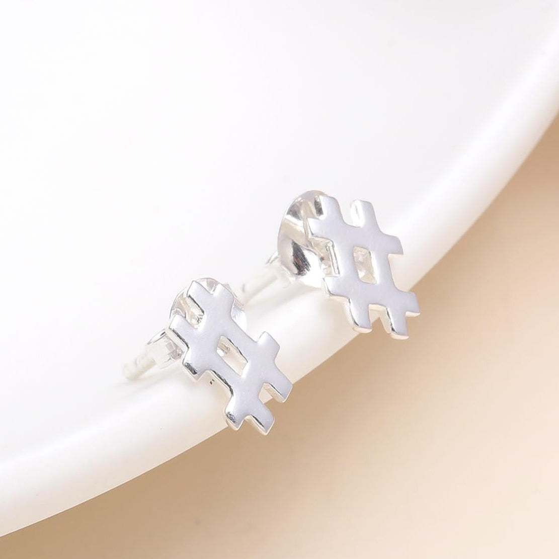 A pair of 925 sterling silver hashtag stud earrings placed on a white surface, with a polished finish.