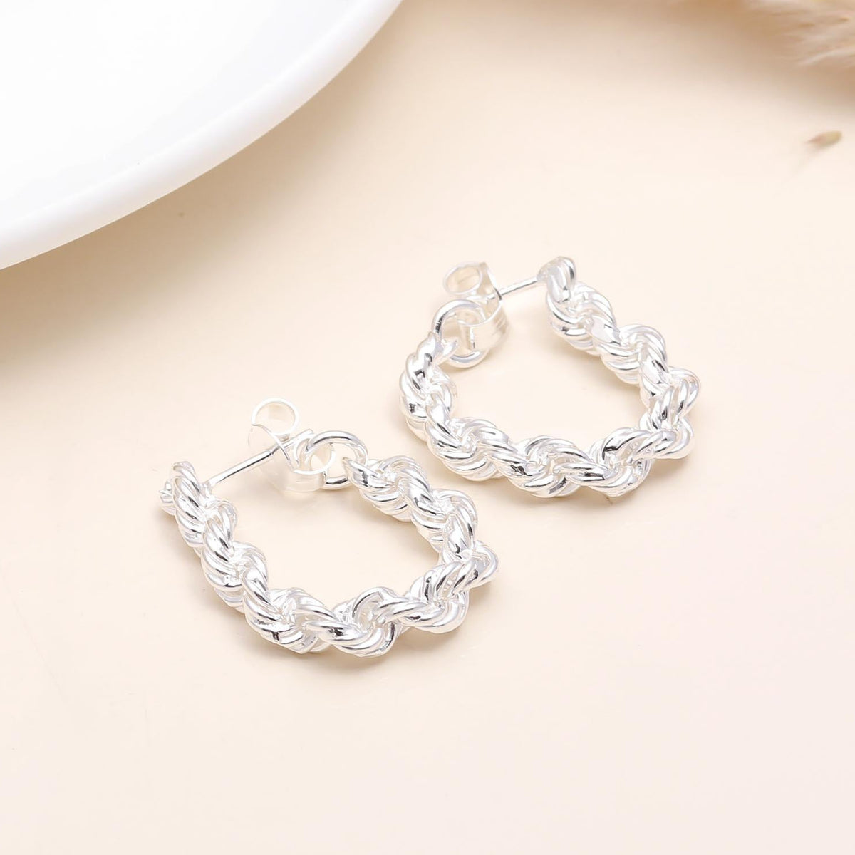 A pair of 925 sterling silver rope twist hoop earrings displayed against a neutral background.