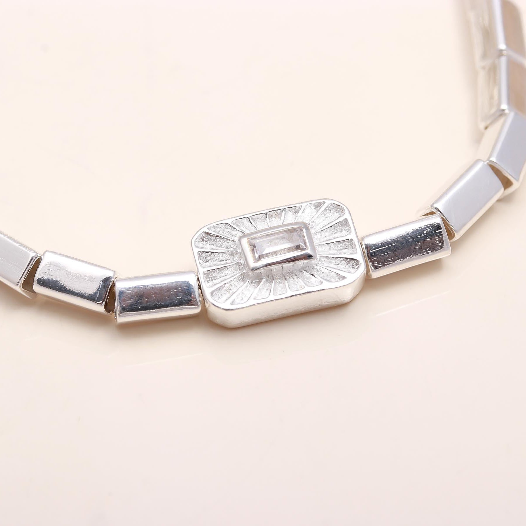 Silver necklace with a rectangular pendant on a light beige background
