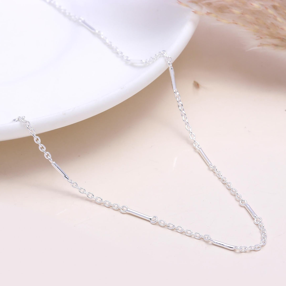 A 925 Sterling Silver Bar Link Chain Necklace laid out on a white surface, showcasing its sleek, delicate design.