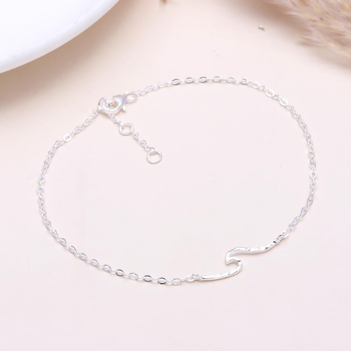 A 925 sterling silver wave chain bracelet displayed on a light background, with delicate wave-like links and an adjustable clasp.
