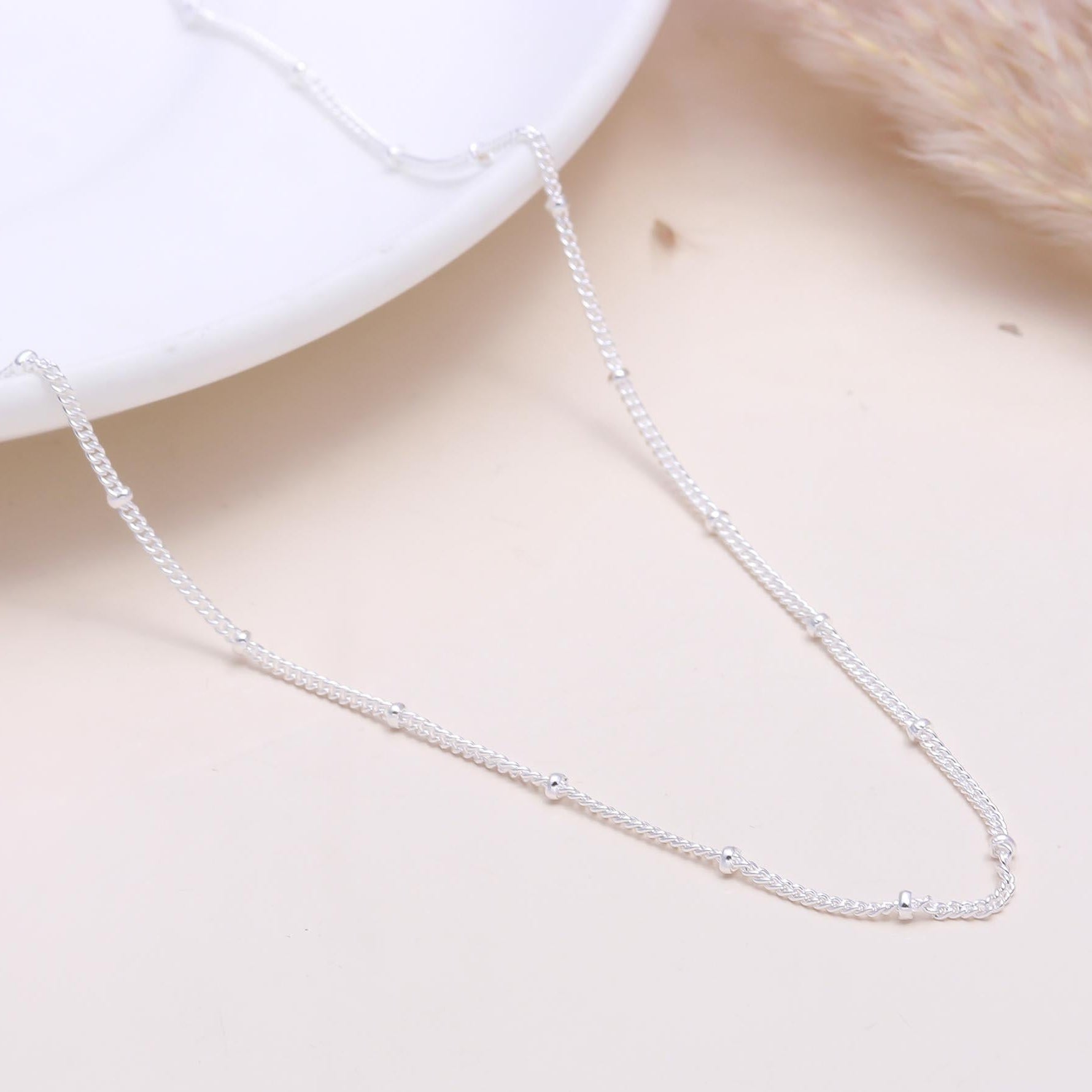 A 925 sterling silver satellite chain necklace with satellite beads spaced along a fine chain, displayed on a white surface.