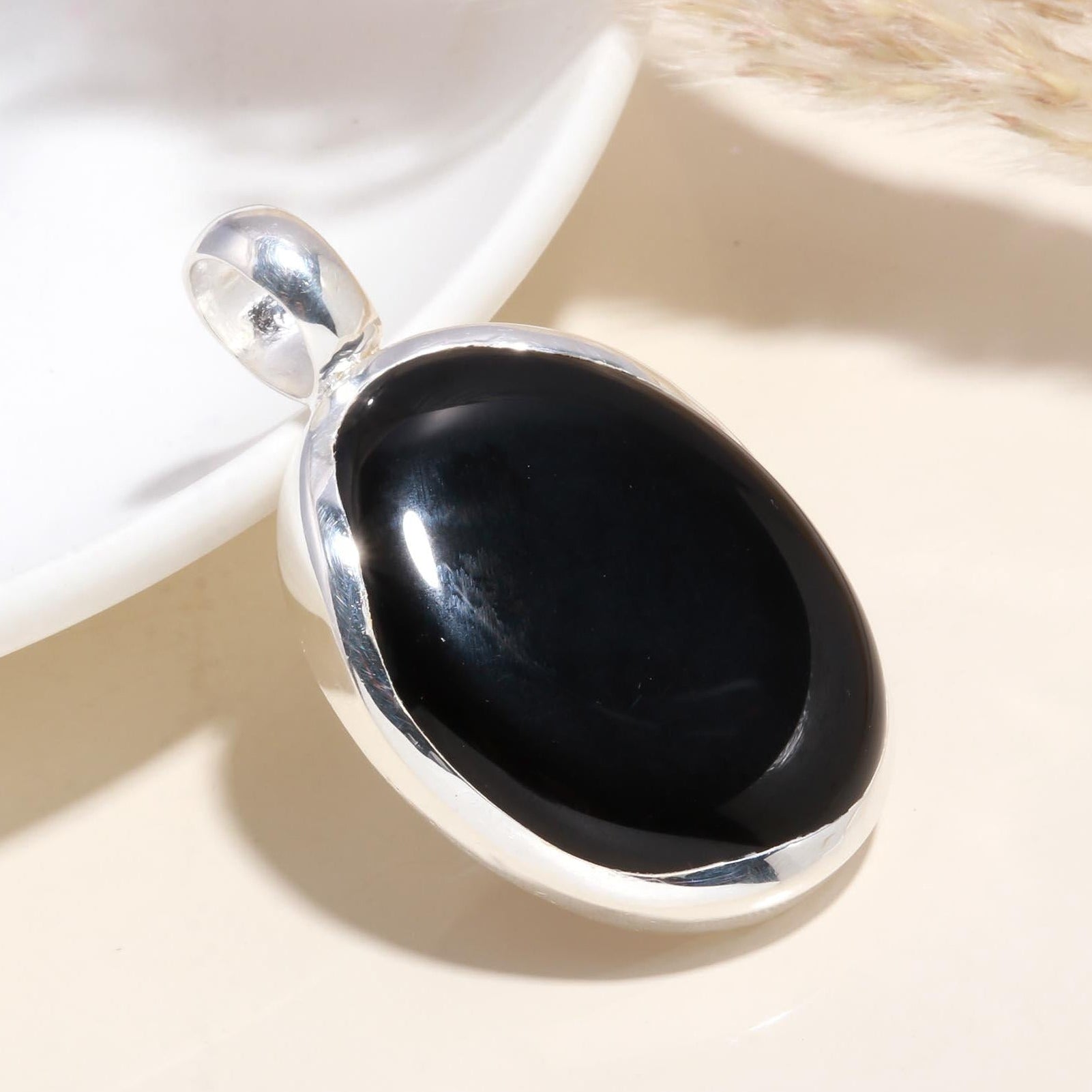 An oval black onyx gemstone pendant set in a 925 sterling silver mounting, displayed against a light background.