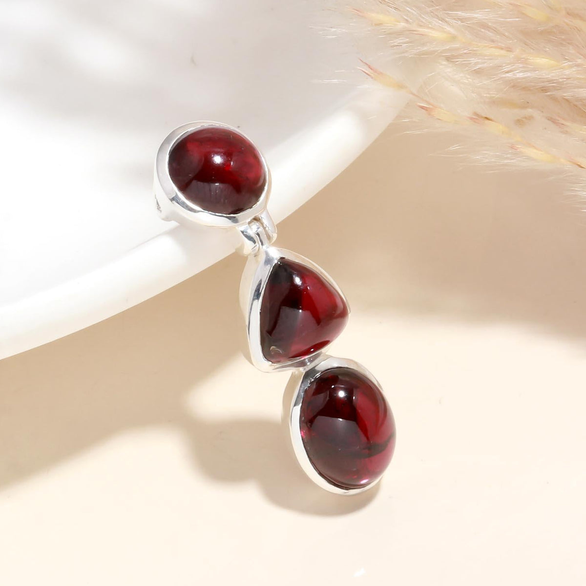 A 925 sterling silver triple garnet drop pendant with a cascading design, featuring three red garnet gemstones.
