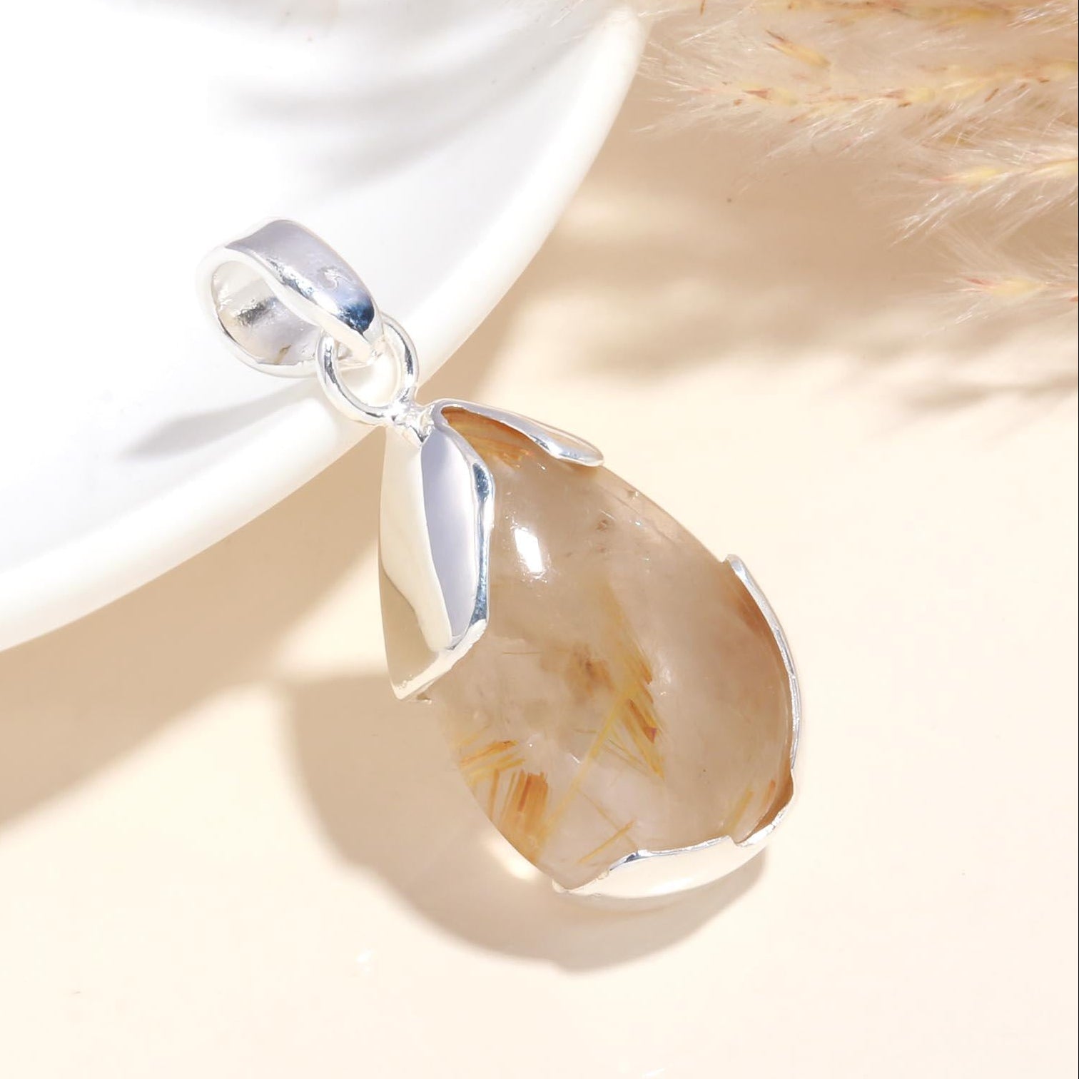 A pear-shaped rutilated quartz pendant set in sterling silver, displayed against a neutral background.