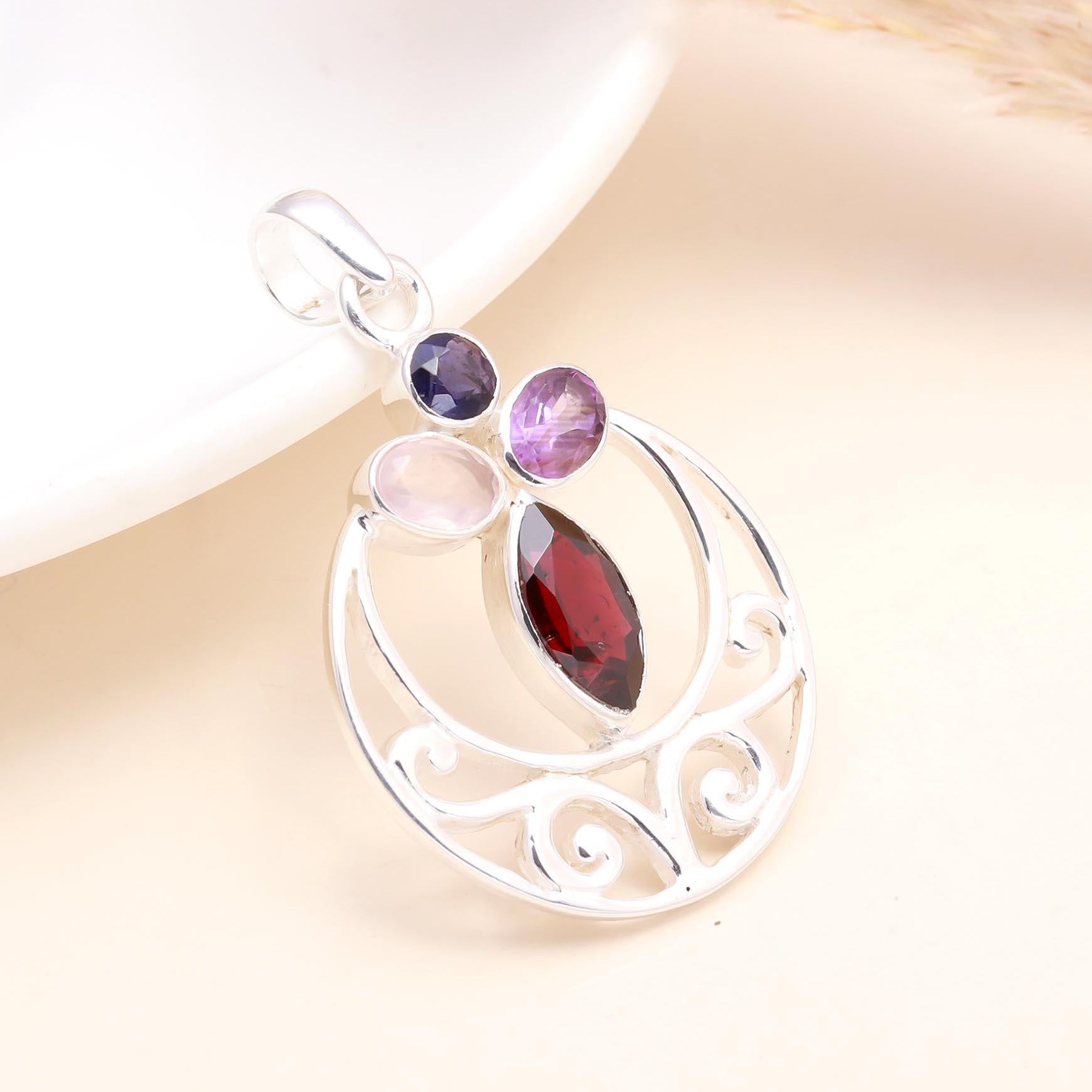 A 925 sterling silver multi-gemstone pendant featuring garnet, amethyst, iolite, and rose quartz arranged in a circular design with a white background.