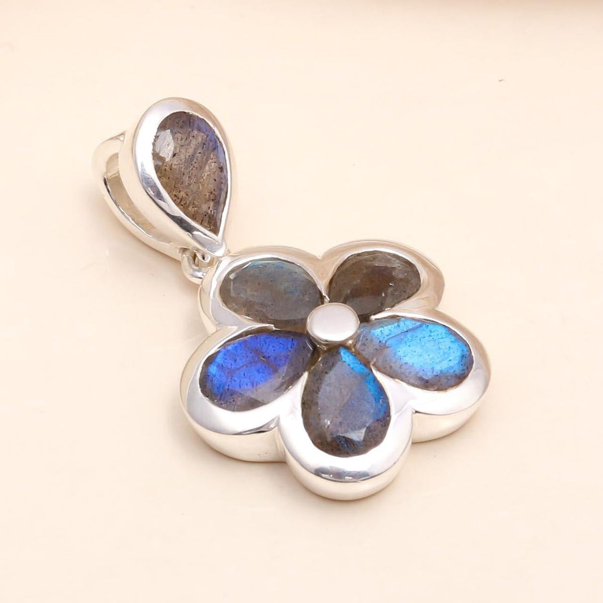 Silver pendant with blue gemstones on a beige background