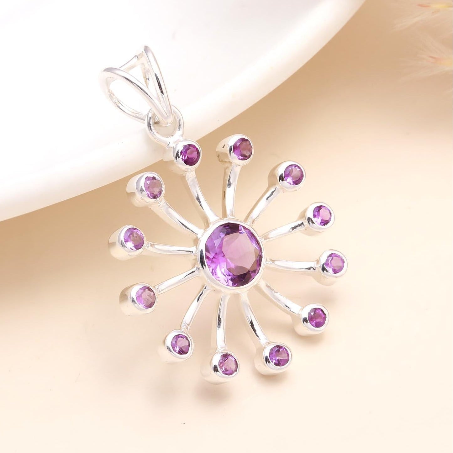 Silver pendant with purple gemstones on a soft beige background