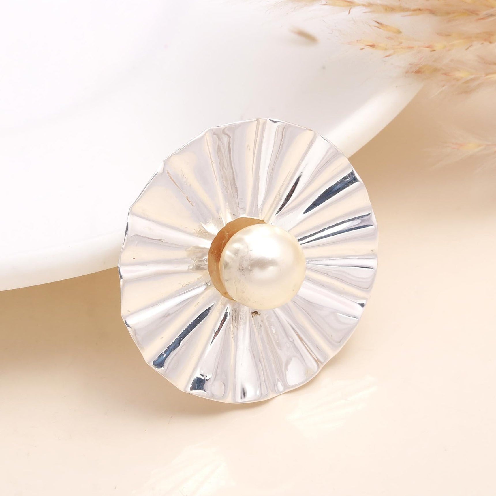 A 925 Sterling Silver Natural Pearl Center Modern Disc Pendant placed on a white surface, with a pearl in the center and a reflective silver surface around it.