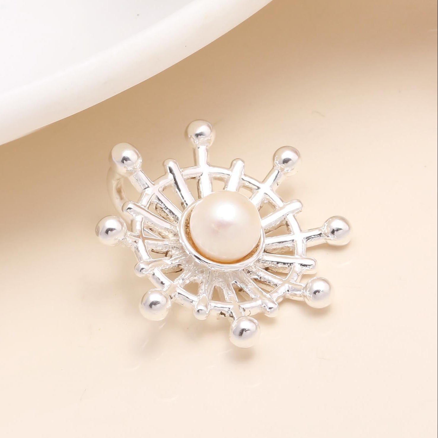 A 925 sterling silver sunburst pendant featuring a central natural freshwater pearl, with intricate silver rays framing the pearl.