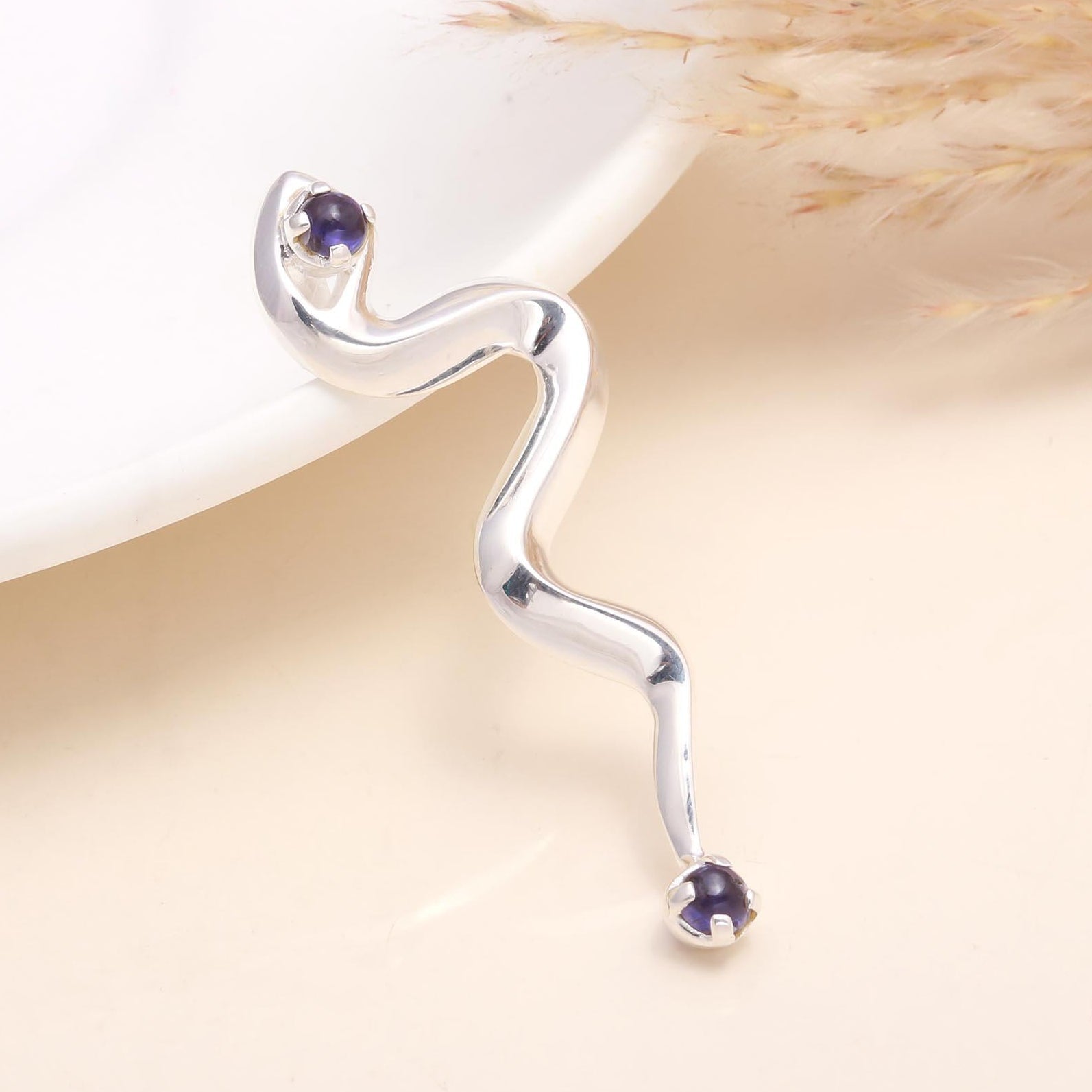 A 925 sterling silver pendant featuring a coiled serpent design with natural amethyst gemstone, displayed against a beige background.