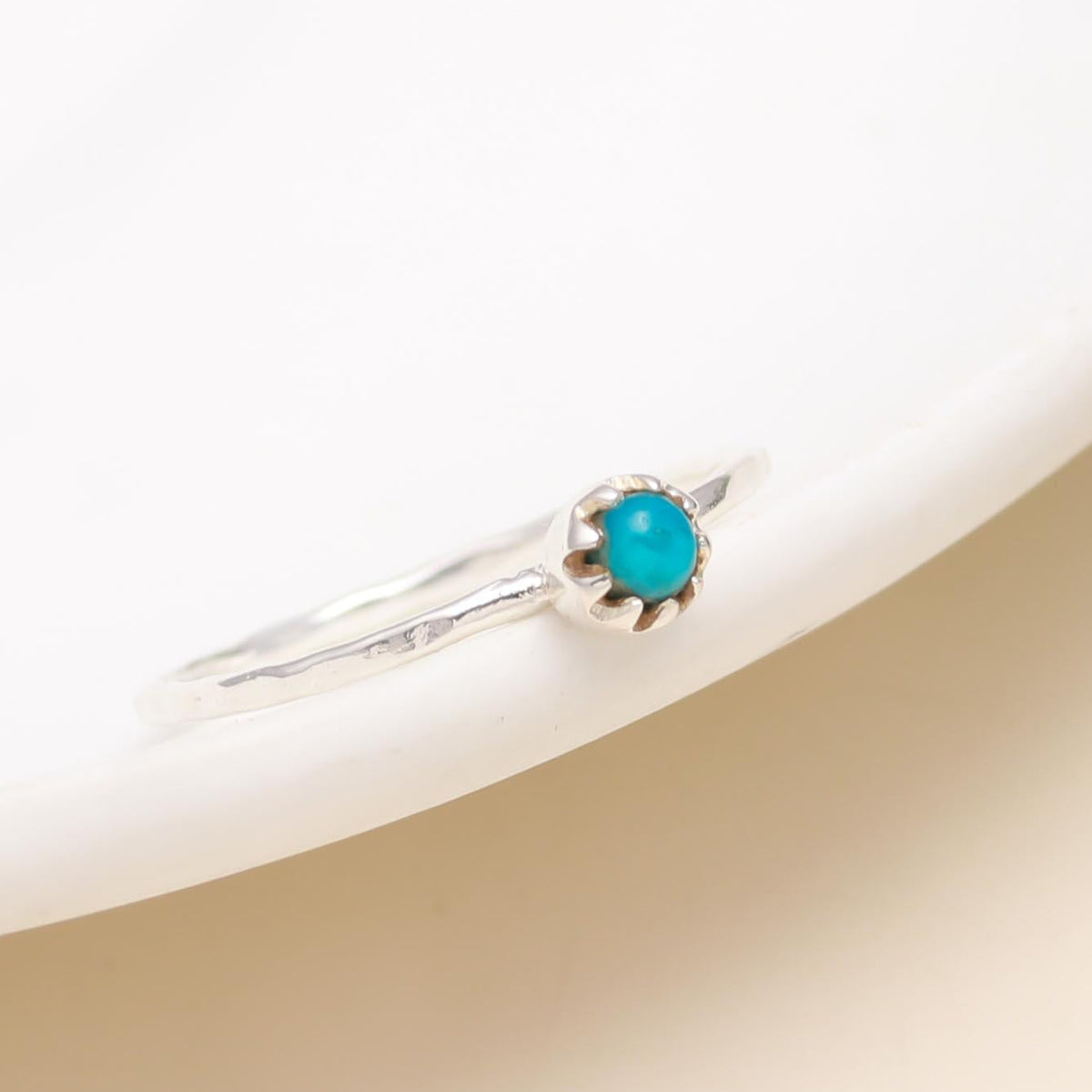 Silver ring with a turquoise stone on a beige background