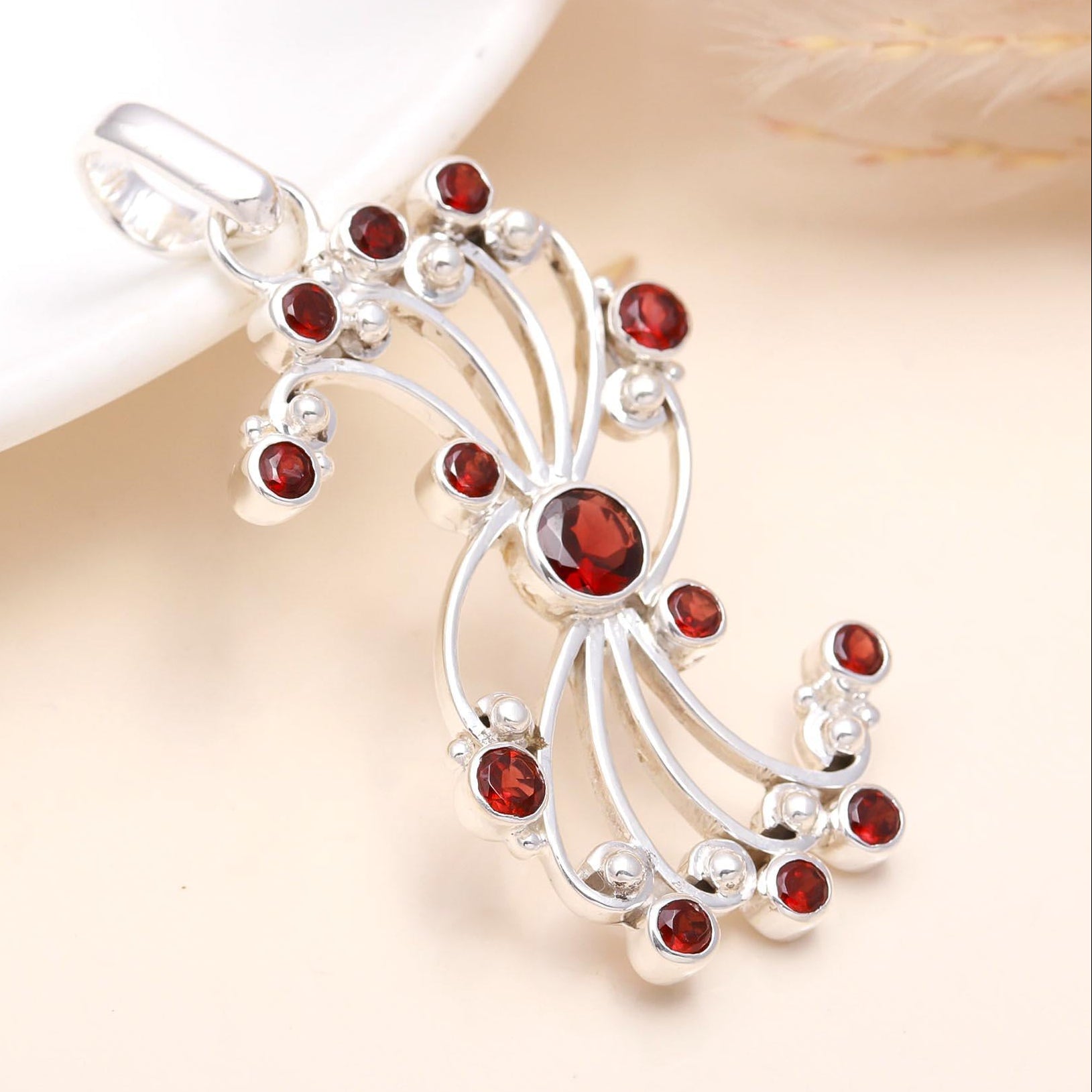 A sterling silver round garnet filigree statement pendant with intricate detailing and red garnet stones.