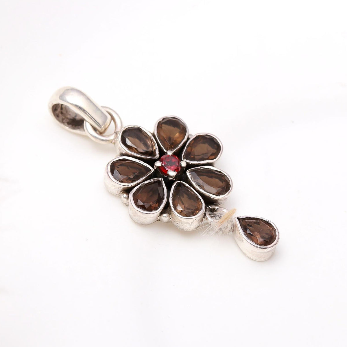 A silver pendant featuring a floral design with smoky quartz petals and a garnet center.