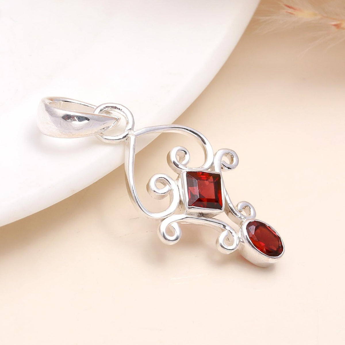A sterling silver vintage garnet filigree statement pendant with ornate silver detailing and a deep-red garnet gemstone, presented on a white surface.