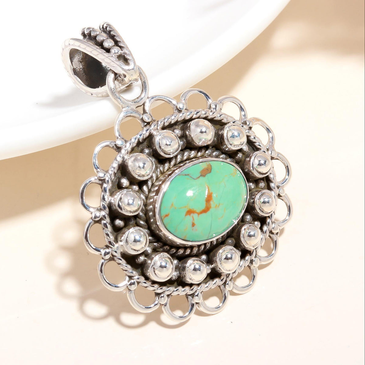 A vintage-inspired sterling silver pendant featuring a natural turquoise gemstone, surrounded by intricate silver detailing.