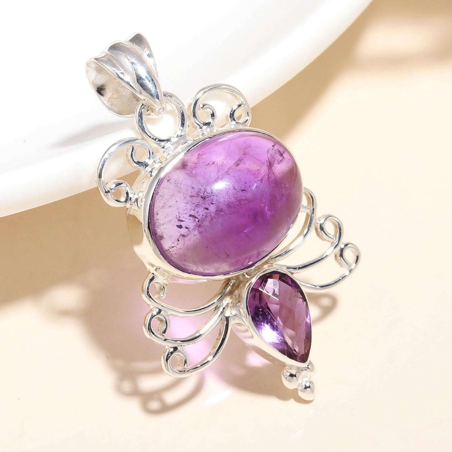 A handmade vintage sterling silver pendant with an amethyst gemstone, showcasing intricate filigree work.